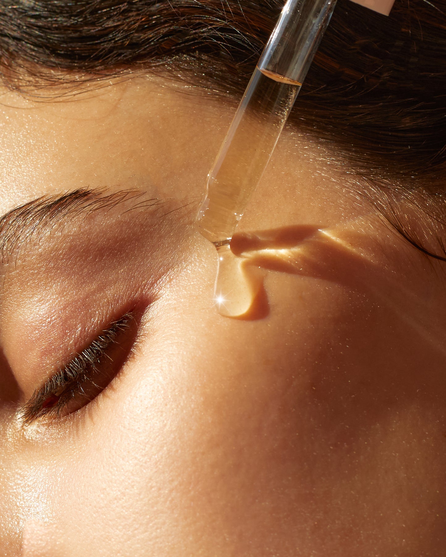 A droplet of The Collagen Serum from SolRay Beauty being applied to a woman's face, highlighting its use in a daily skincare routine.